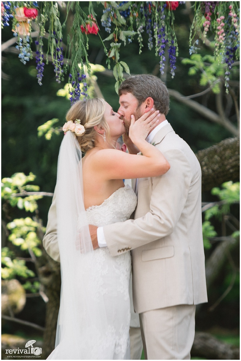 Bride and groom under arbor of flowers